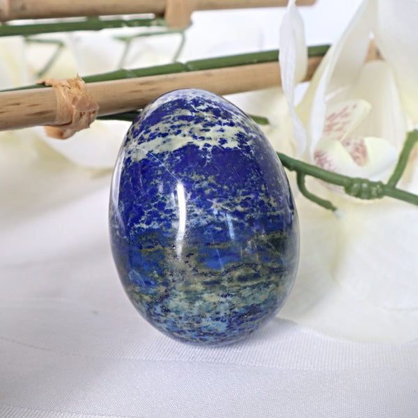 Large Lapis Lazuli egg with golden pyrite flecks on a white background
