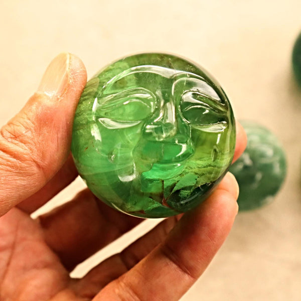 Fluorite crystal orb with moon face design for spiritual energy