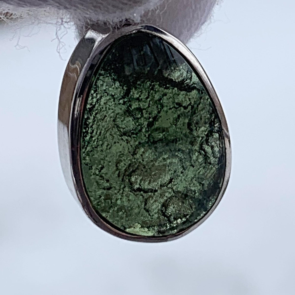 Natural moldavite pendant showing raw backside texture