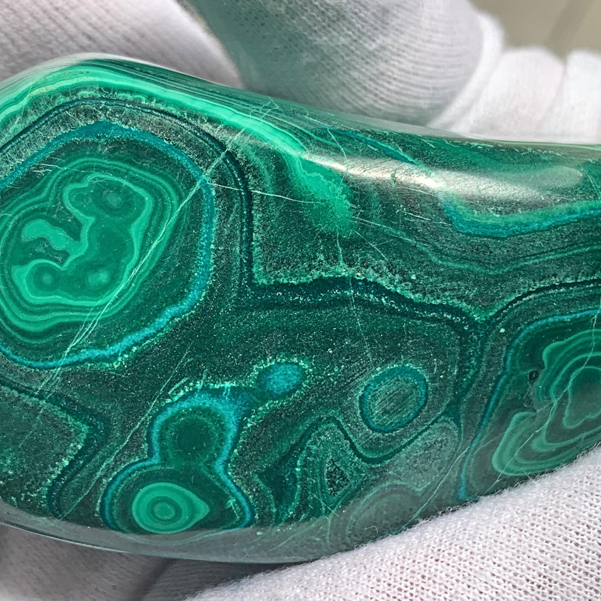 Ethically sourced raw malachite gemstone polished into a smooth organic freeform shape.
