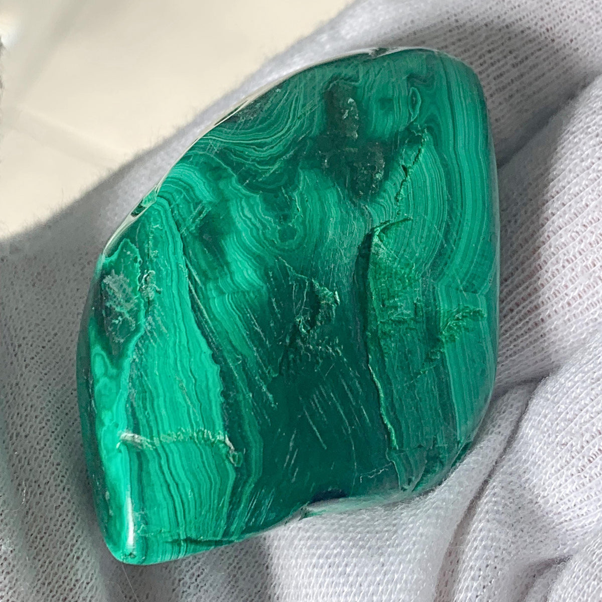 Close-up of a malachite crystal with vibrant light and dark green banding and a high-gloss finish.