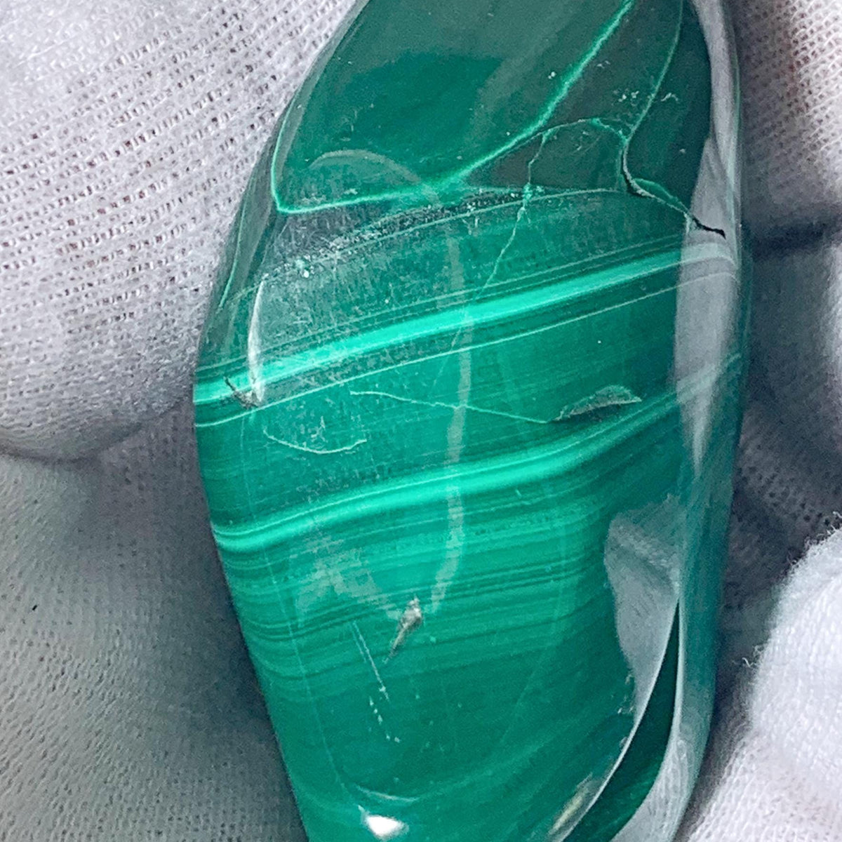 Ethically sourced raw malachite gemstone polished into a smooth organic freeform shape.