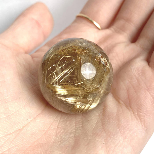 Natural rutilated quartz crystal sphere close up