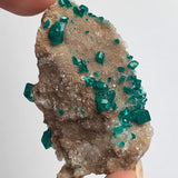 green dioptase crystals across natural matrix