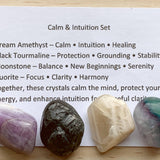Themed healing crystal sets displayed inside open cardboard gift boxes with properties cards