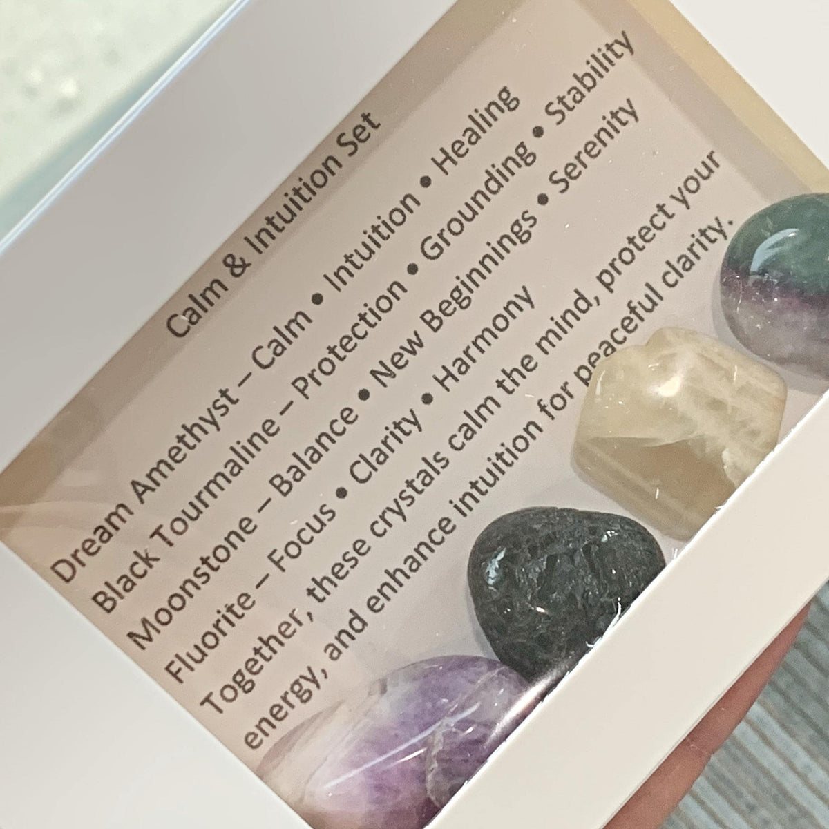 Calming crystals sets displayed inside open cardboard gift boxes with properties cards