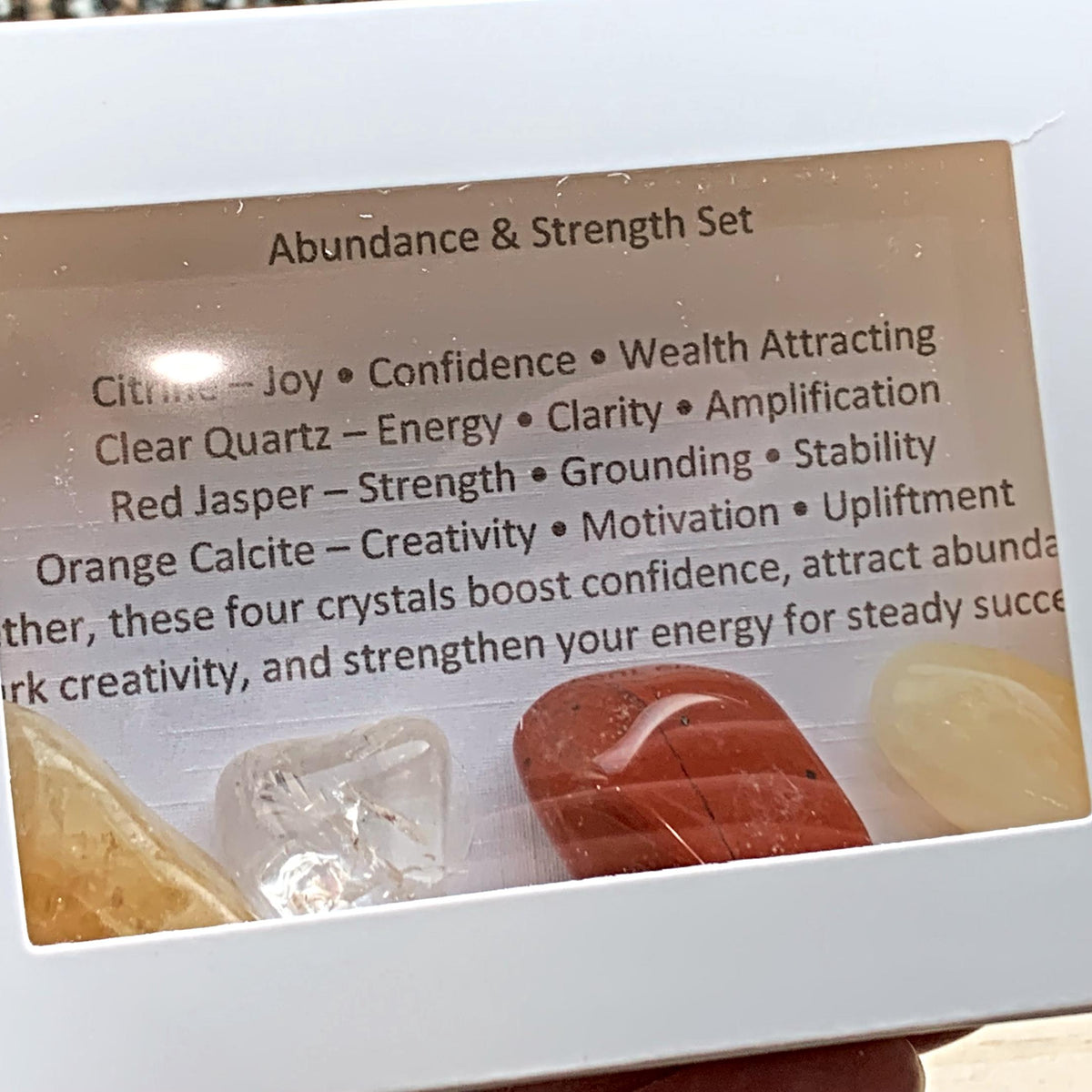 Themed healing crystal sets displayed inside open cardboard gift boxes with properties cards