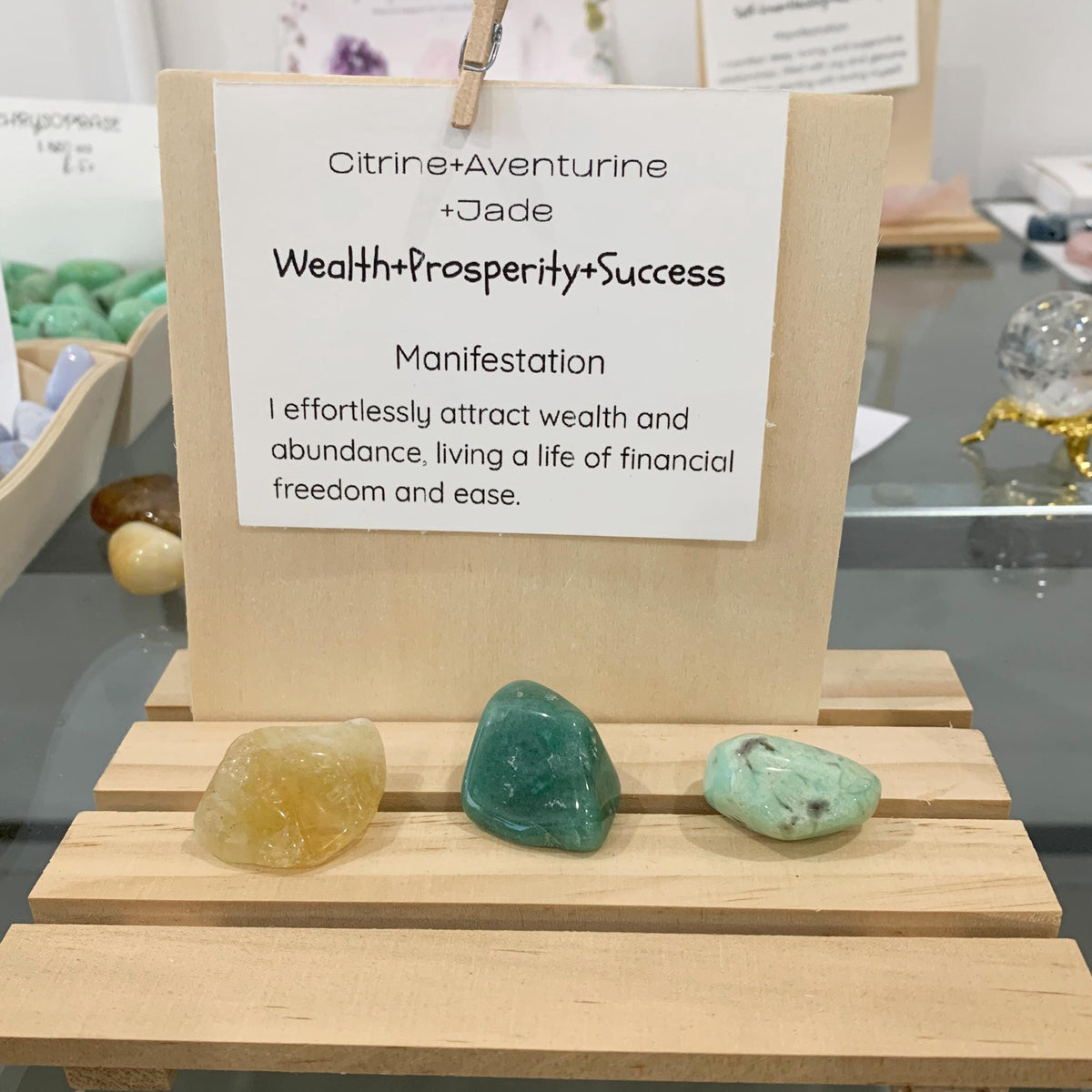 Close up of a golden citrine, aventurine and jade tumbled stone resting on a wealth manifestation card