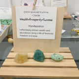 Close up of a golden citrine, aventurine and jade tumbled stone resting on a wealth manifestation card