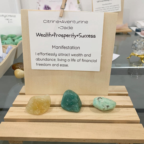 Close up of a golden citrine, aventurine and jade tumbled stone resting on a wealth manifestation card