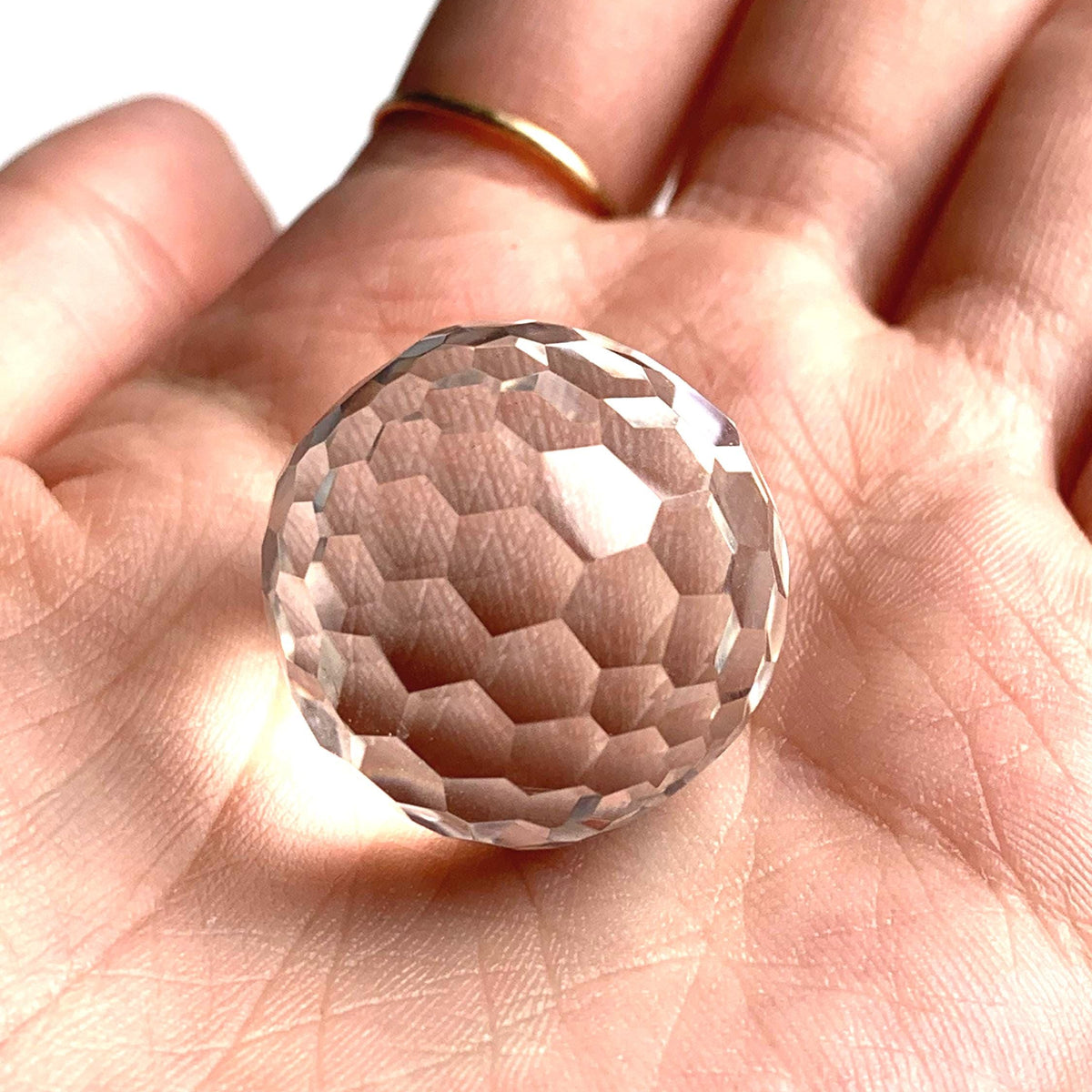 Close up of a gem grade diamond cut clear quartz ball with zero internal inclusions.