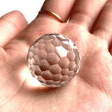 Close up of a gem grade diamond cut clear quartz ball with zero internal inclusions.