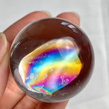 Small high clarity rainbow quartz sphere with polished reflective surface and natural inclusions