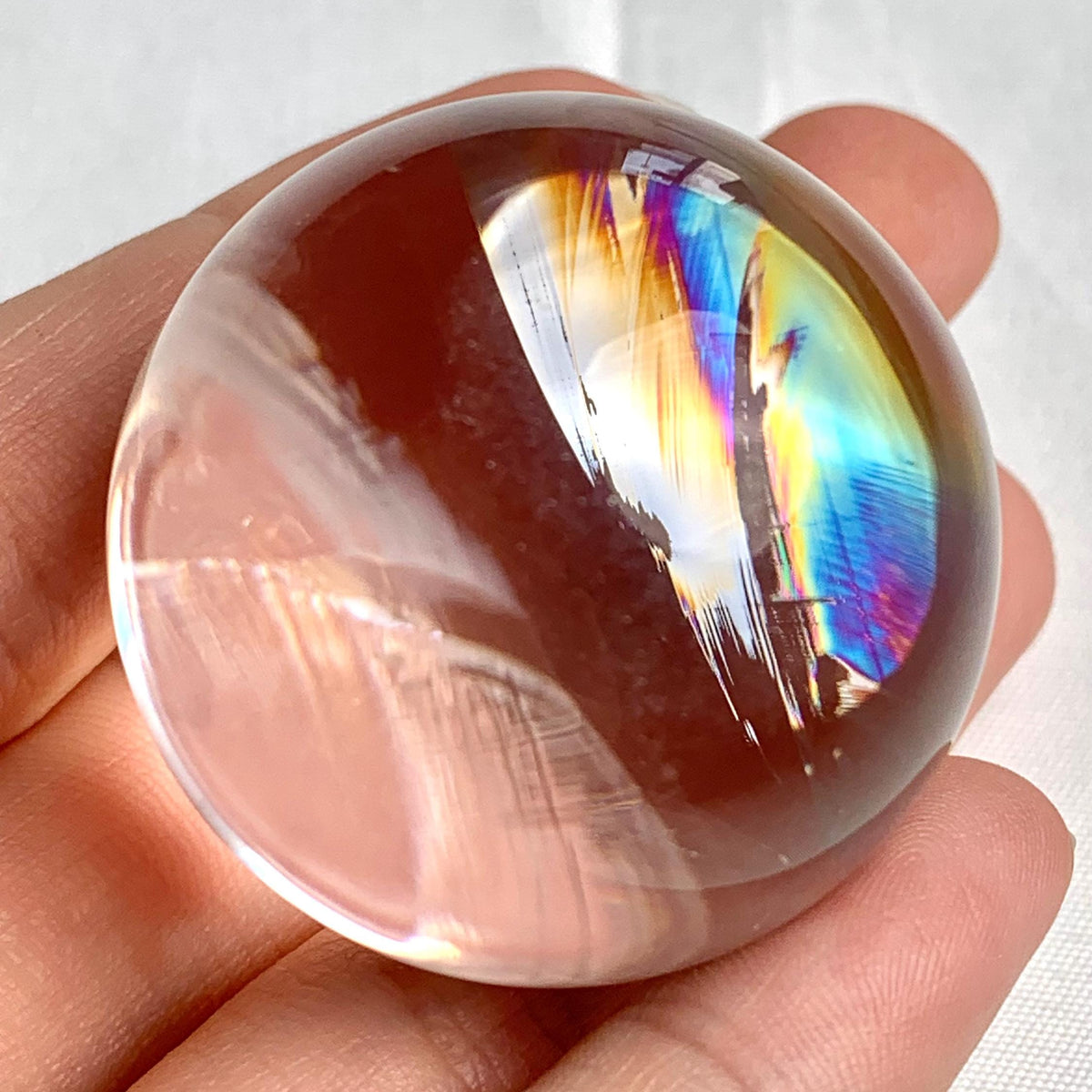 Polished clear quartz sphere showing delicate internal rainbow flashes