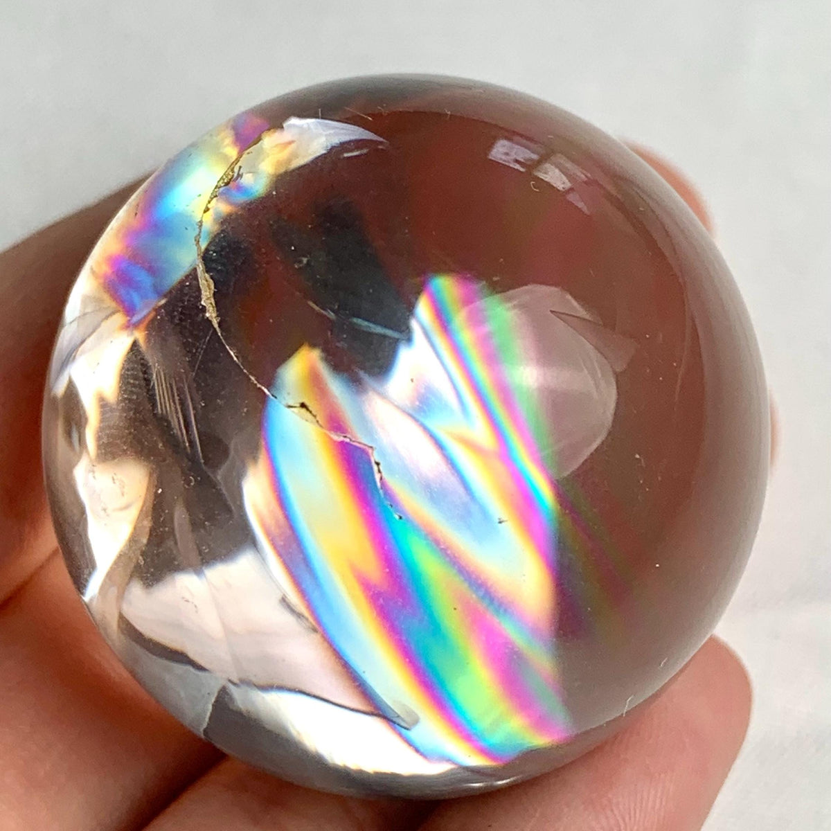 High clarity quartz crystal ball showing soft rainbow reflections