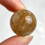 Small rutilated quartz sphere with glowing golden rutile threads inside