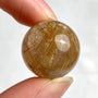 Small rutilated quartz sphere with glowing golden rutile threads inside