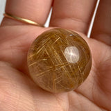 Close-up rutilated quartz sphere with fine golden rutile needles suspended in clear quartz