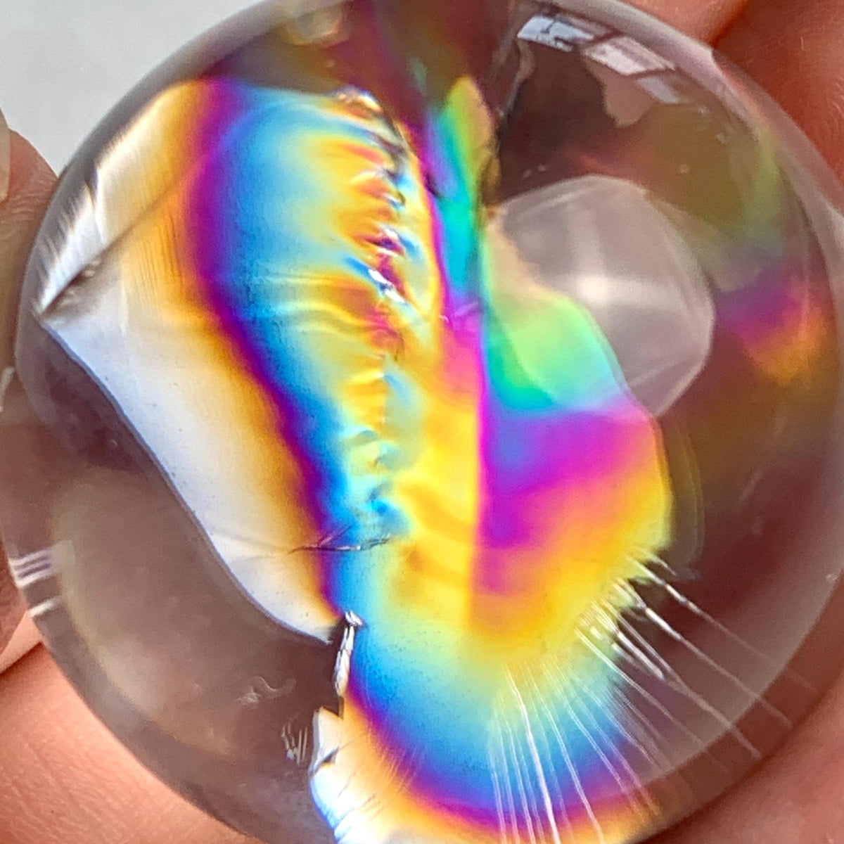 Natural clear quartz sphere displaying vibrant internal rainbow flashes