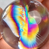 Natural clear quartz sphere displaying vibrant internal rainbow flashes