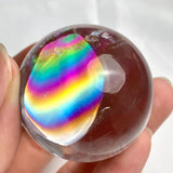 Natural quartz sphere displaying vibrant rainbow flashes throughout crystal