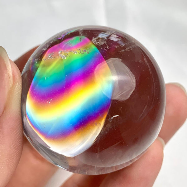 Natural quartz sphere displaying vibrant rainbow flashes throughout crystal
