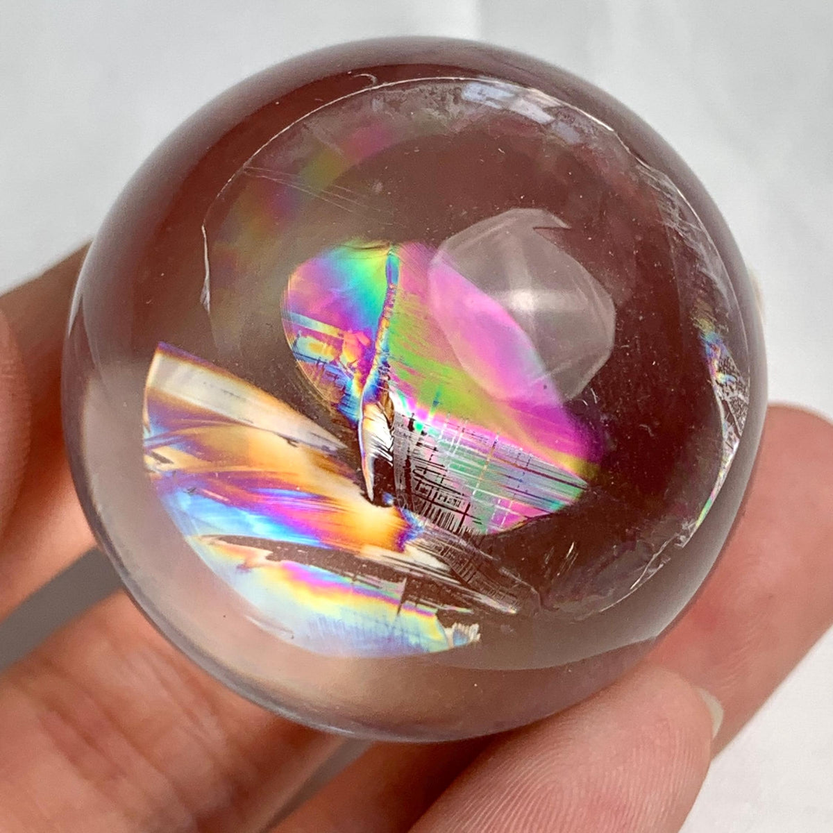 Small decorative rainbow quartz sphere displayed on crystal stand