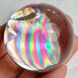 Small rainbow quartz crystal sphere with polished finish and natural light-reflecting inclusions