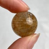 Compact collector rutilated quartz sphere with visible internal rutile patterns