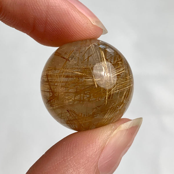 Compact collector rutilated quartz sphere with visible internal rutile patterns