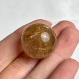 Clear quartz sphere showing soft golden rutile light reflections