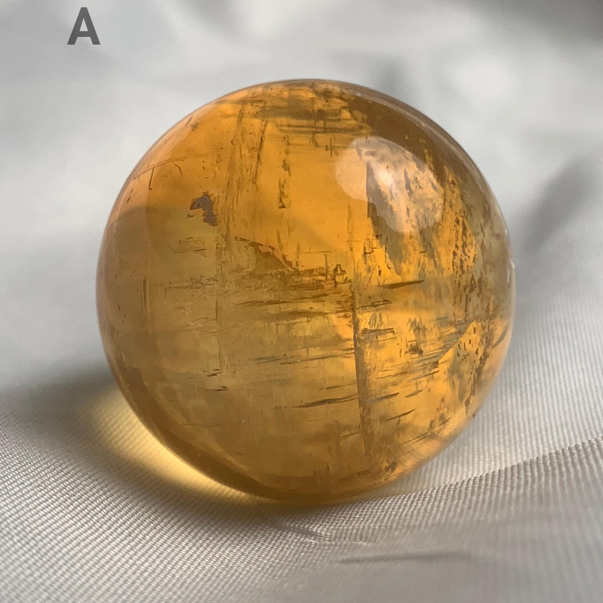 Honey calcite sphere displaying natural rainbow flash