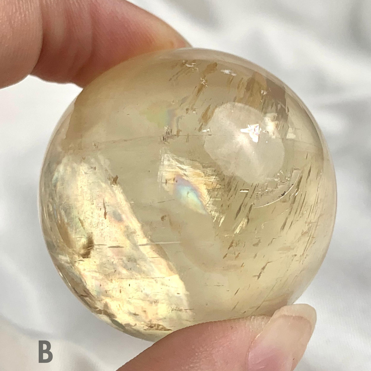 Rainbow honey calcite sphere under natural light