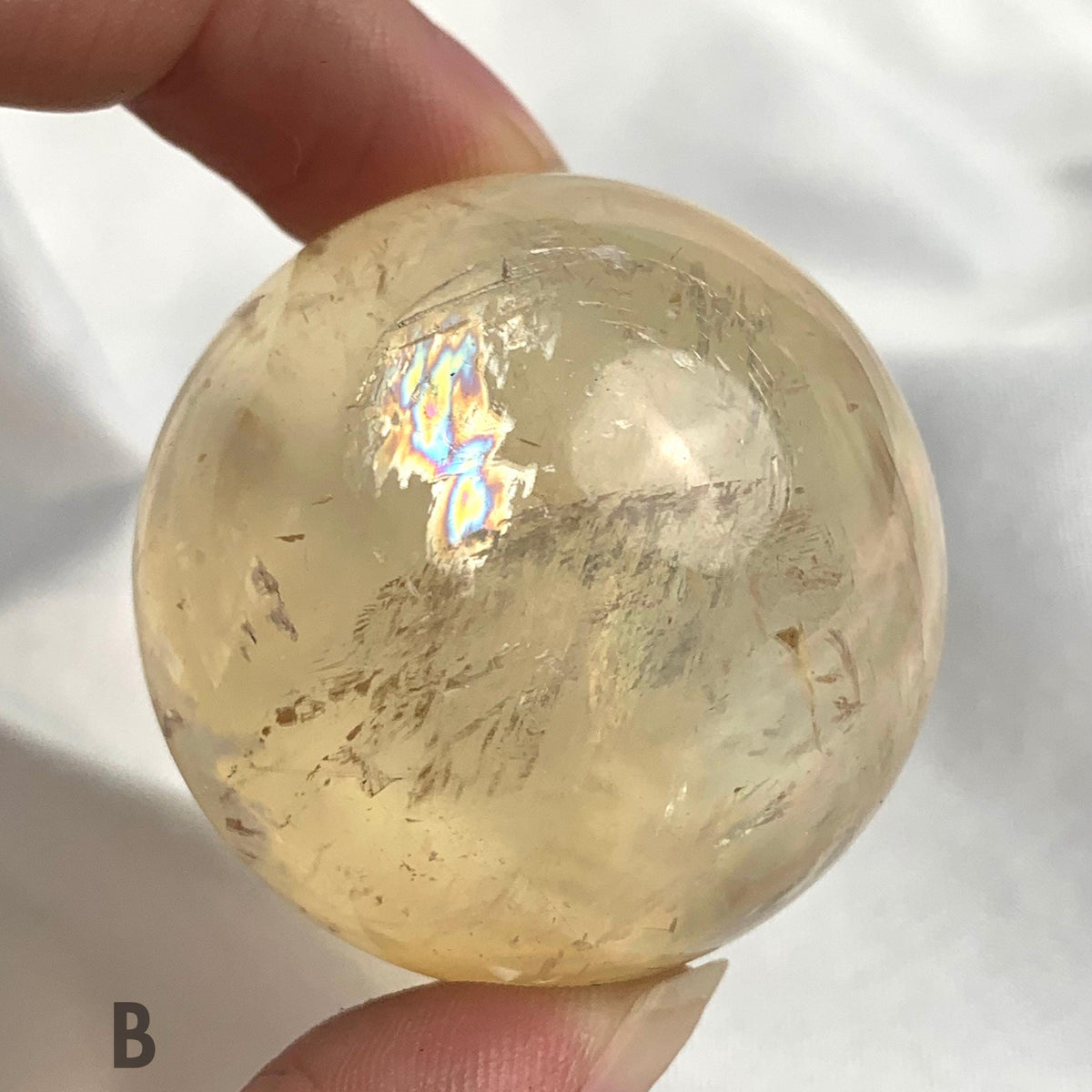 Polished rainbow calcite sphere on display