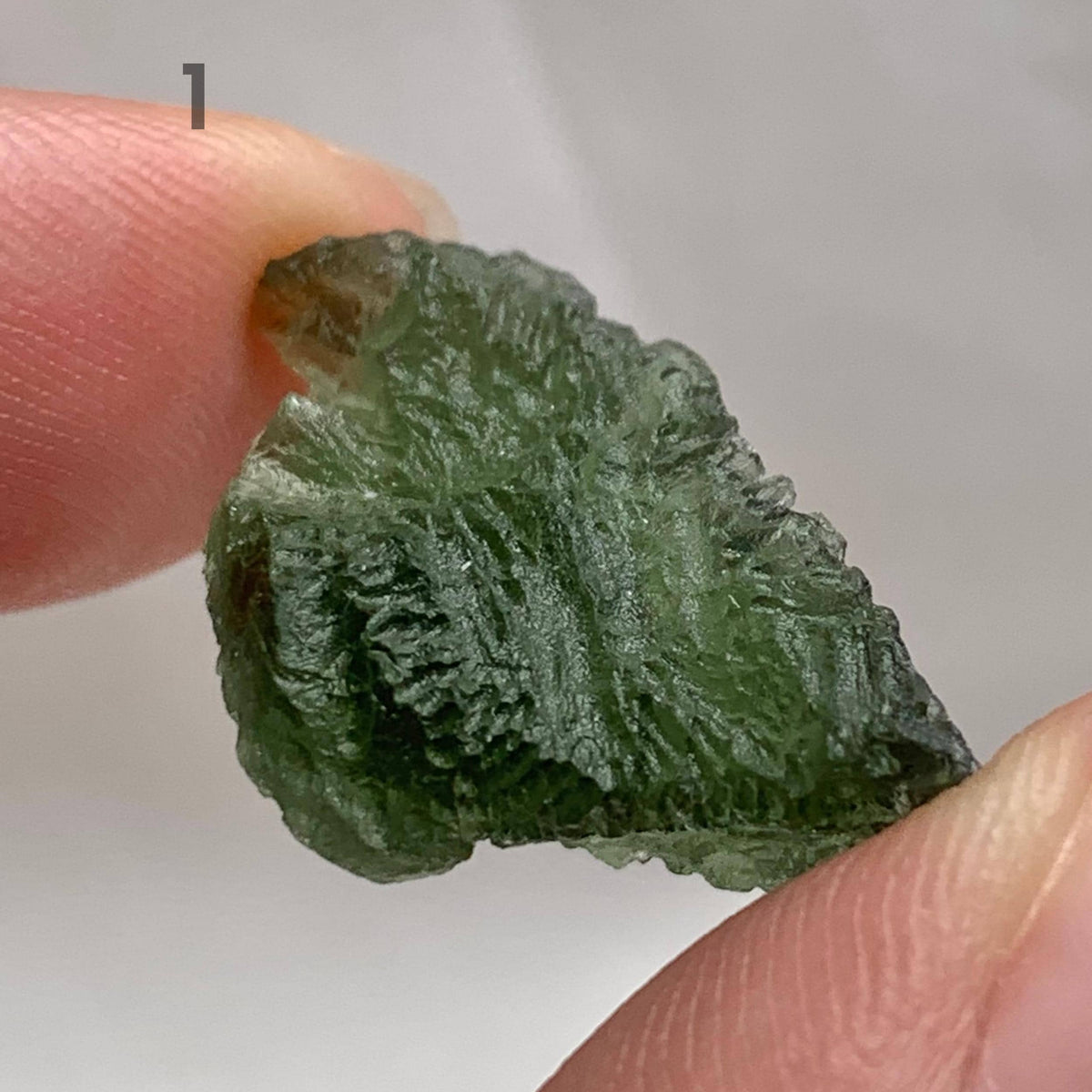 Raw Moldavite stone displaying natural etched surface details
