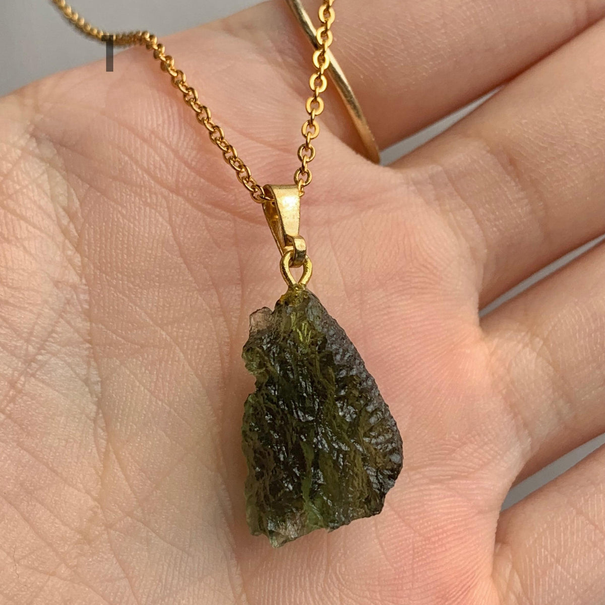 Natural unpolished moldavite jewelry showcasing authentic surface features