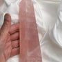 Large pink rose quartz obelisk tower with square base on white background