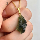 Genuine moldavite pendant close up displaying raw organic formation