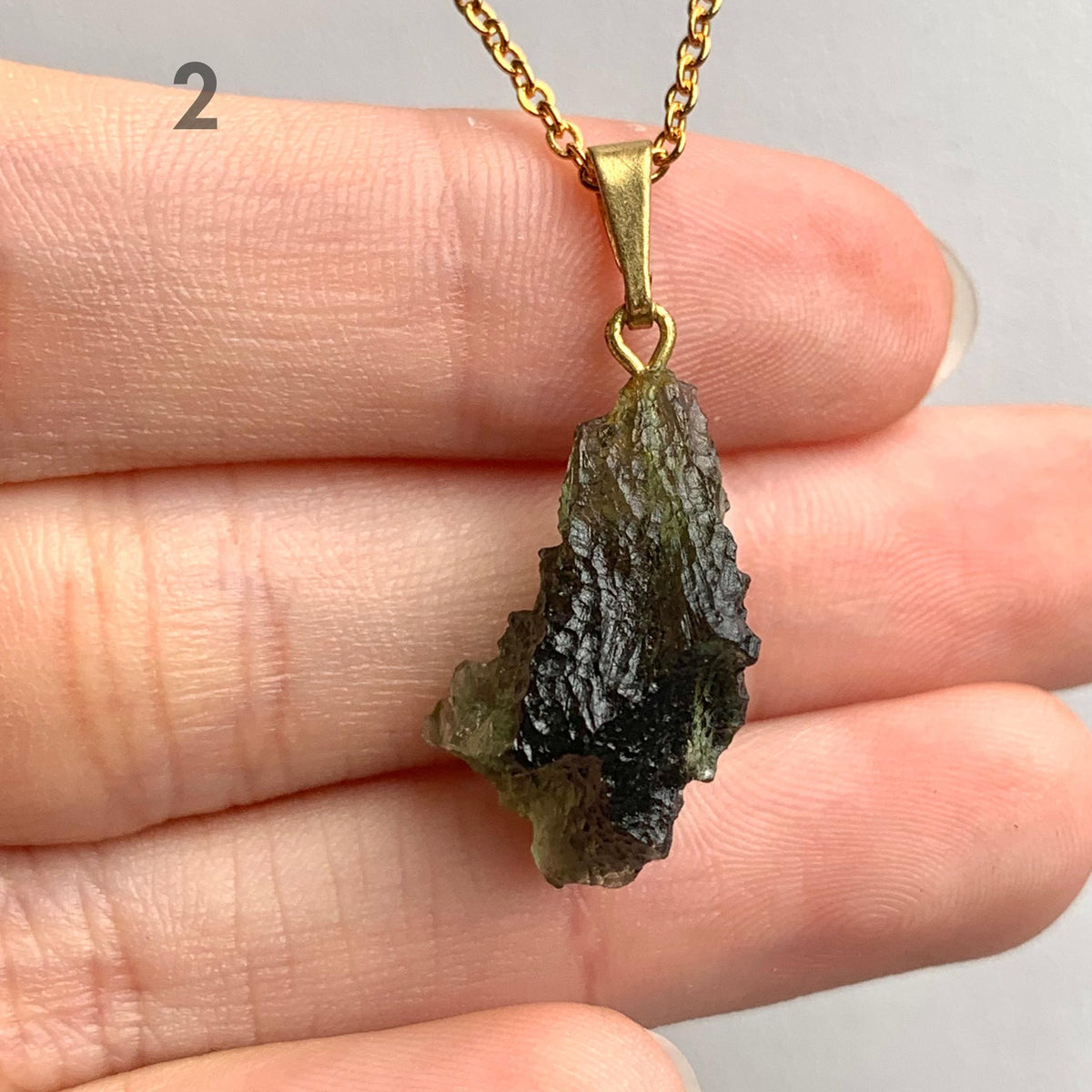 Raw Czech moldavite pendant necklace photographed against neutral background