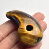 Handheld photo displaying the size and rich luster of the carved Tiger Eye magatama stone.