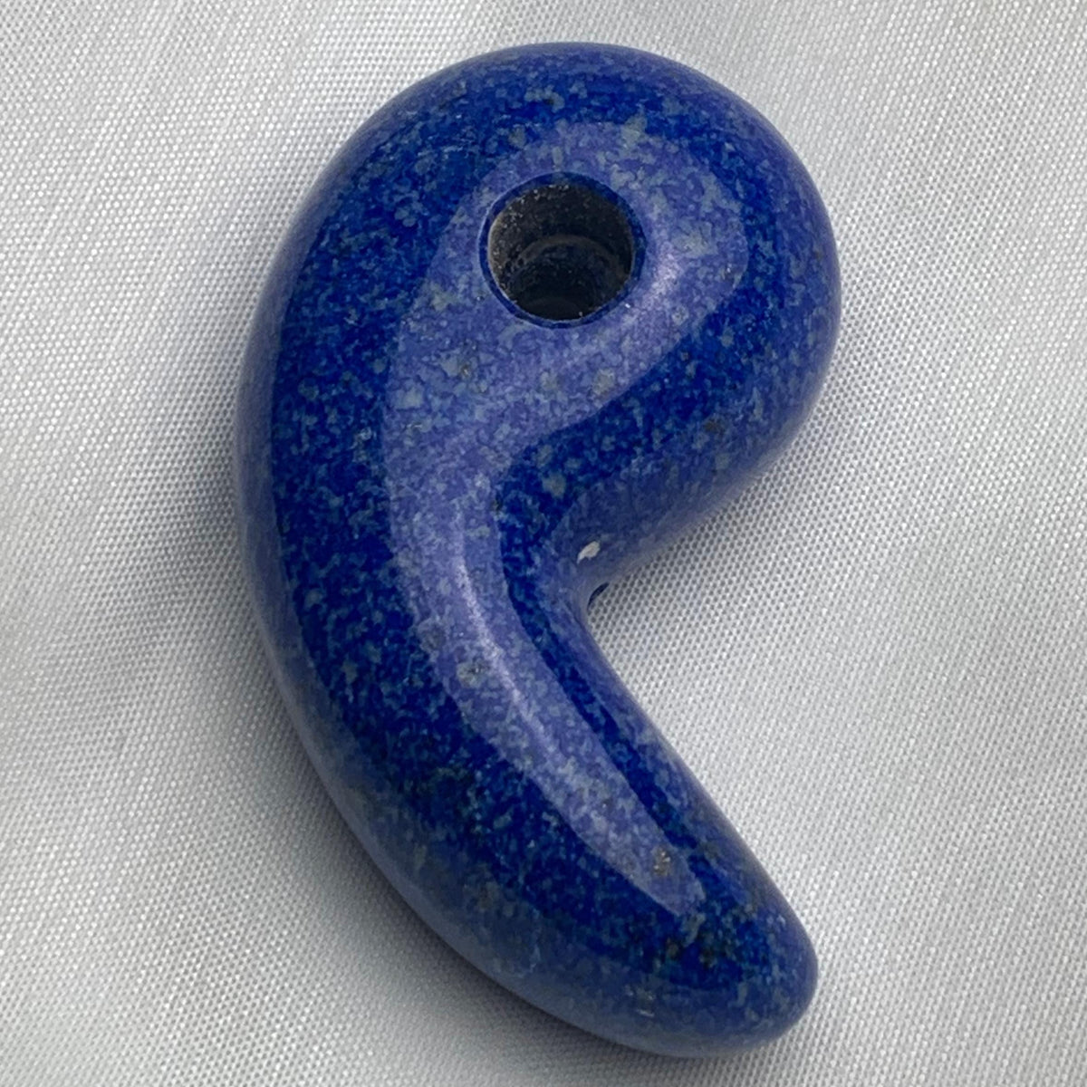 Polished 60mm Lapis Lazuli magatama carving on a white background