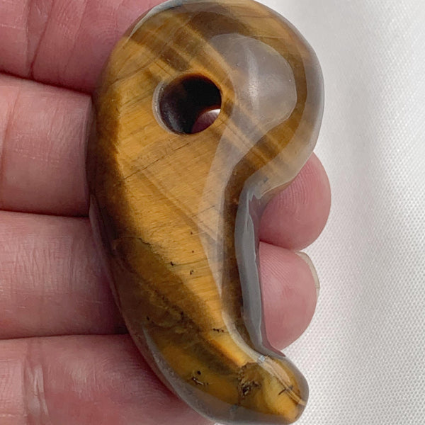 Handheld photo displaying the size and rich luster of the carved Tiger Eye magatama stone.