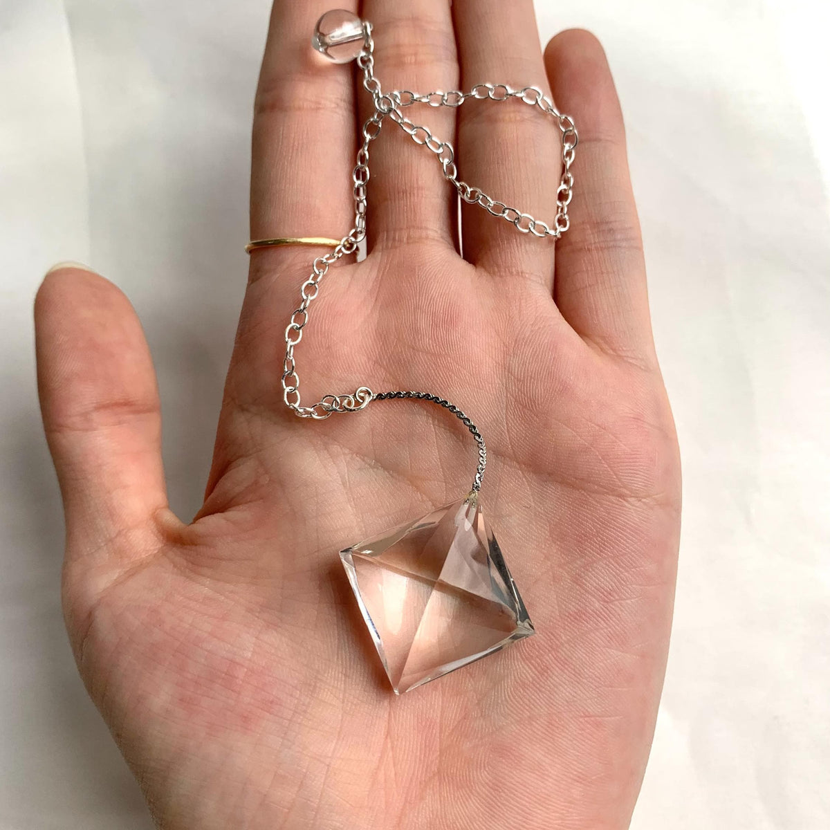 Small clear quartz dowsing pendulum with geometric faceted surface