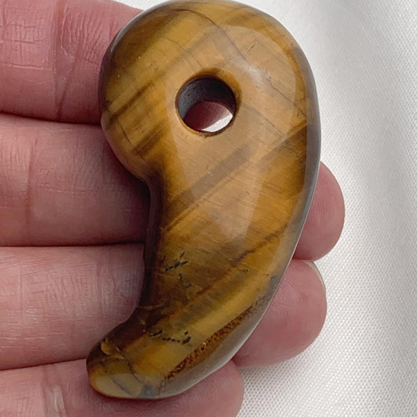 Smooth 50mm golden brown Tiger Eye magatama carving showing vibrant silky chatoyancy.