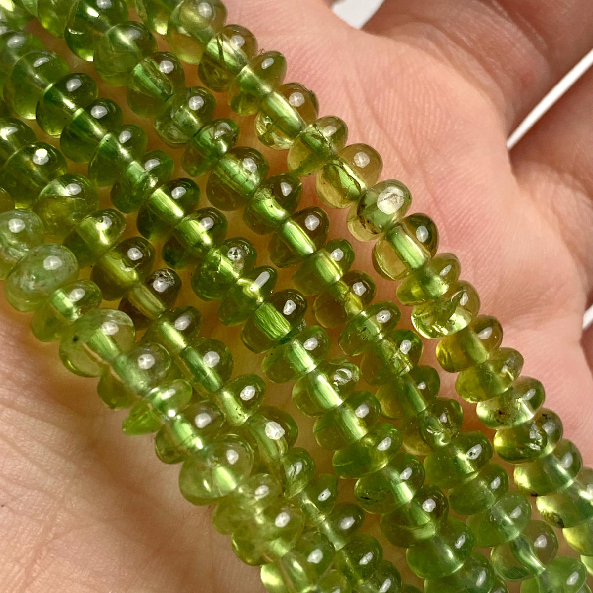Close-up of 5mm peridot beads in a smooth rondelle shape