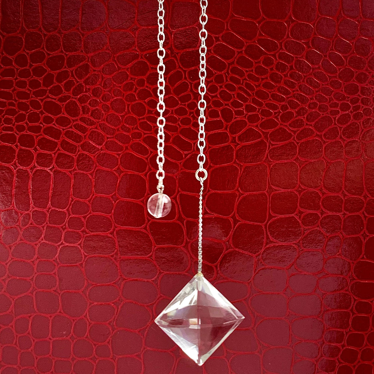 Clear quartz pendulum featuring a symmetrical faceted crystal design