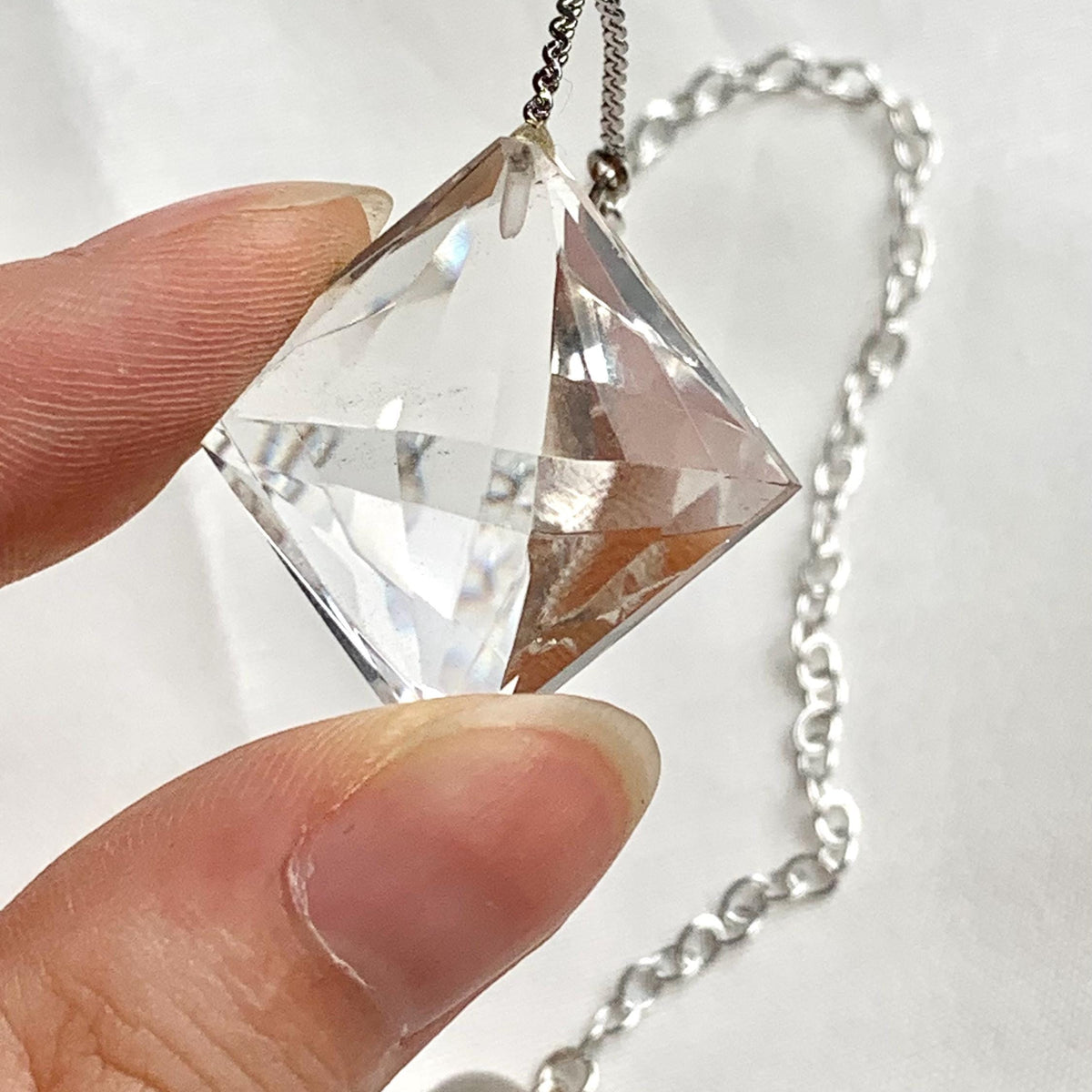 Clear quartz crystal pendulum shown with its 200mm chain