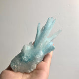 Blue aragonite mineral cluster held to showcase scale and 5-inch length.