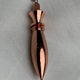 Close side detail of the cap and ring on a pure copper pendulum, sleek spindle profile for scrying and divination