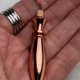 Handheld scale view, pure copper pendulum resting in palm, shows size, shine, and copper pendulum with chain detail